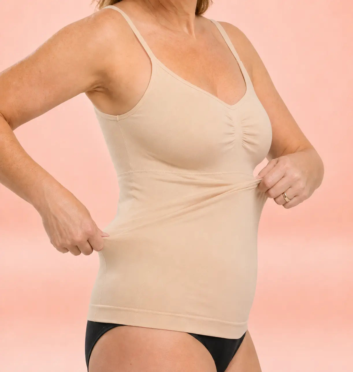 Woman over 60 stretching the beige OnlyShape Everyday Support Cami to show soft fabric, built-in support and comfortable fit with black underwear Image